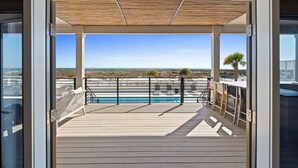 A deck with a pool, outdoor seating, and a view of the beach. - Costa-Florida: 7 Bedrooms, Private Pool, Community Pool and Gym (Mexico Beach)