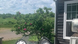 En træterrasse med et metalbord og stole, en potteplante og et grillområde.