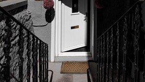 Una escalera que lleva a una puerta blanca con un buzón y una placa con un número.