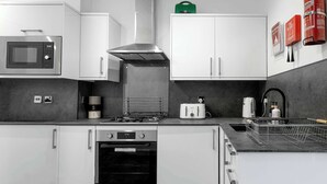 Una cocina moderna con armarios blancos, microondas, estufa a gas, horno y lavaplatos.