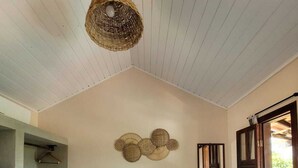A bedroom with a bed, a hanging light fixture, a wardrobe, and a window with shutters. - Pousada Oceano Caraiva (Porto Seguro)
