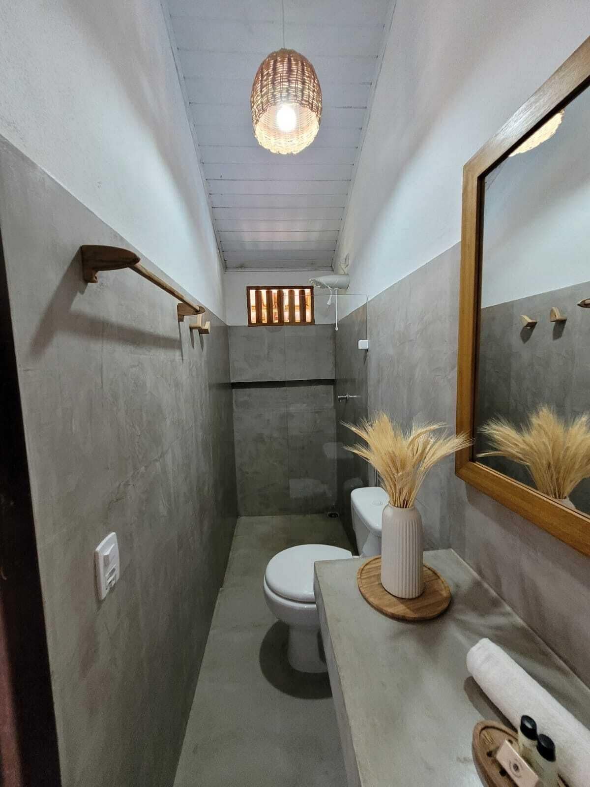 Un baño pequeño con ducha, inodoro y un espejo grande.