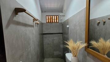 Un baño pequeño con ducha, inodoro y un espejo grande.