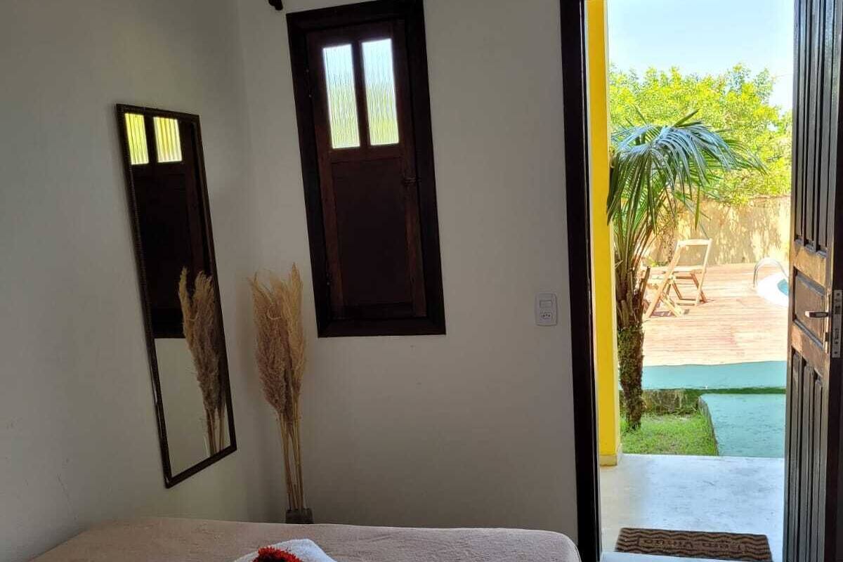 Ein Schlafzimmer mit Bett, Fenster, Tür und Blick ins Freie.