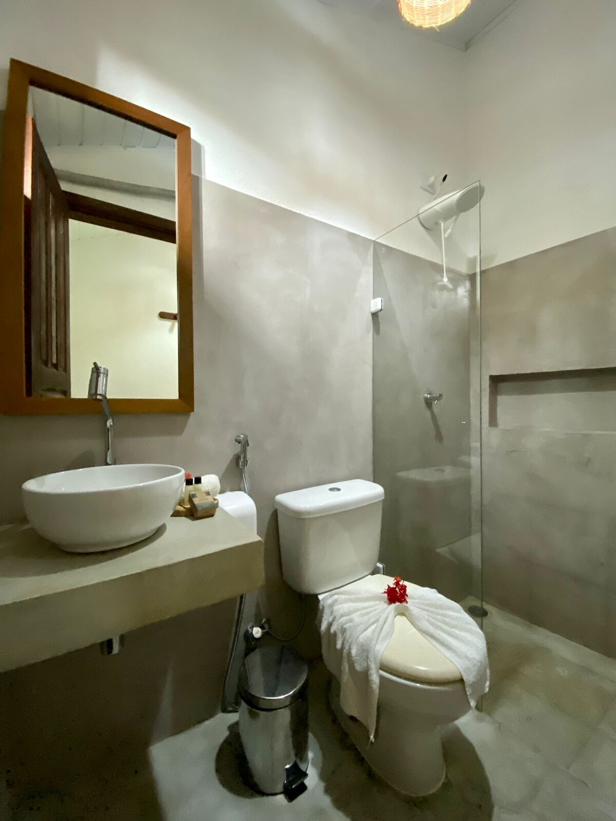 A modern bathroom with a large mirror, a sink, a toilet, and a shower.