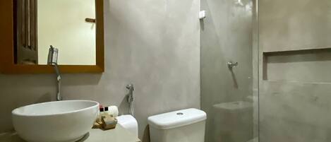 Un baño moderno con un espejo grande, un lavamanos, un inodoro y una ducha.