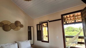 A bedroom with a bed, a woven ceiling light, a window with shutters, and a view of greenery outside. - Pousada Oceano Caraiva (Porto Seguro)