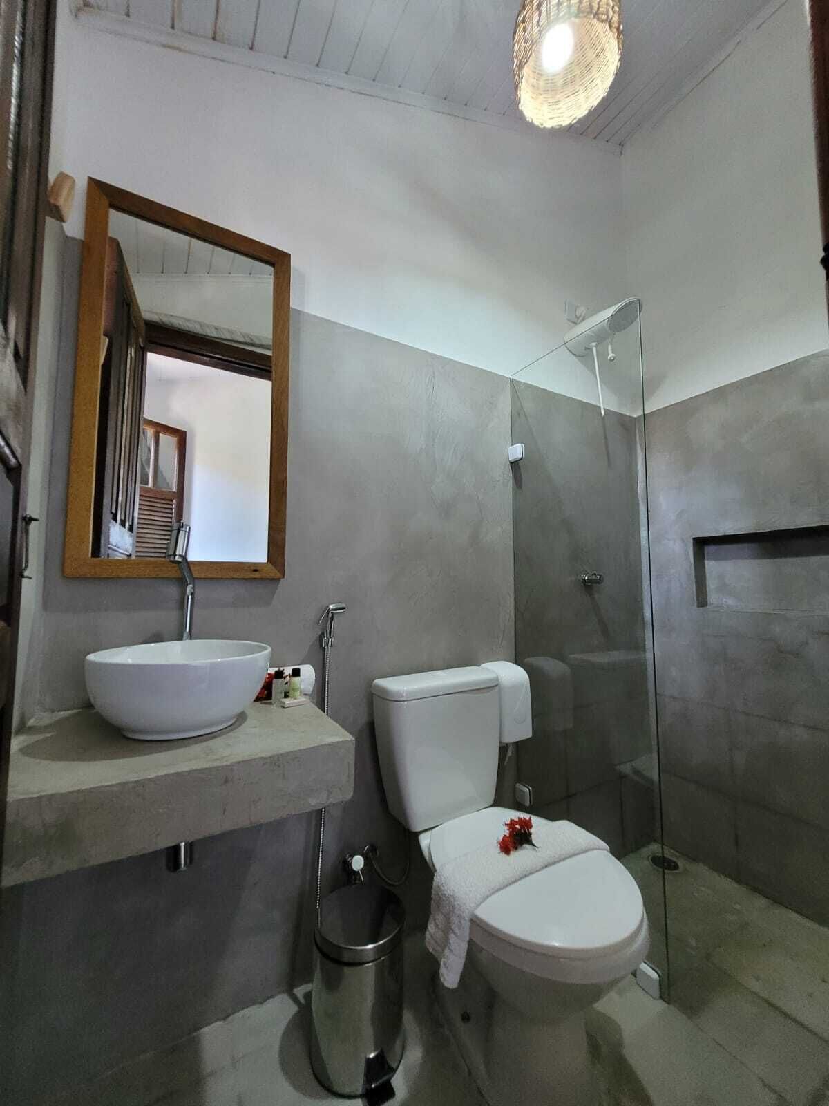 Une salle de bain avec un grand miroir, un lavabo blanc, des toilettes et une douche à parois de verre.