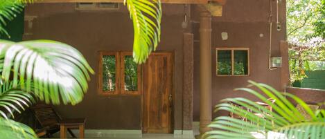 Una casa con puerta de madera, dos ventanas y un porche.