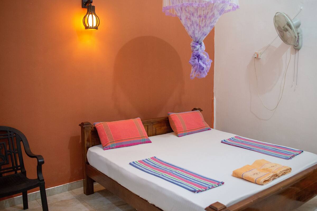 A bed with a white sheet, two pillows, a striped blanket, and a folded towel.