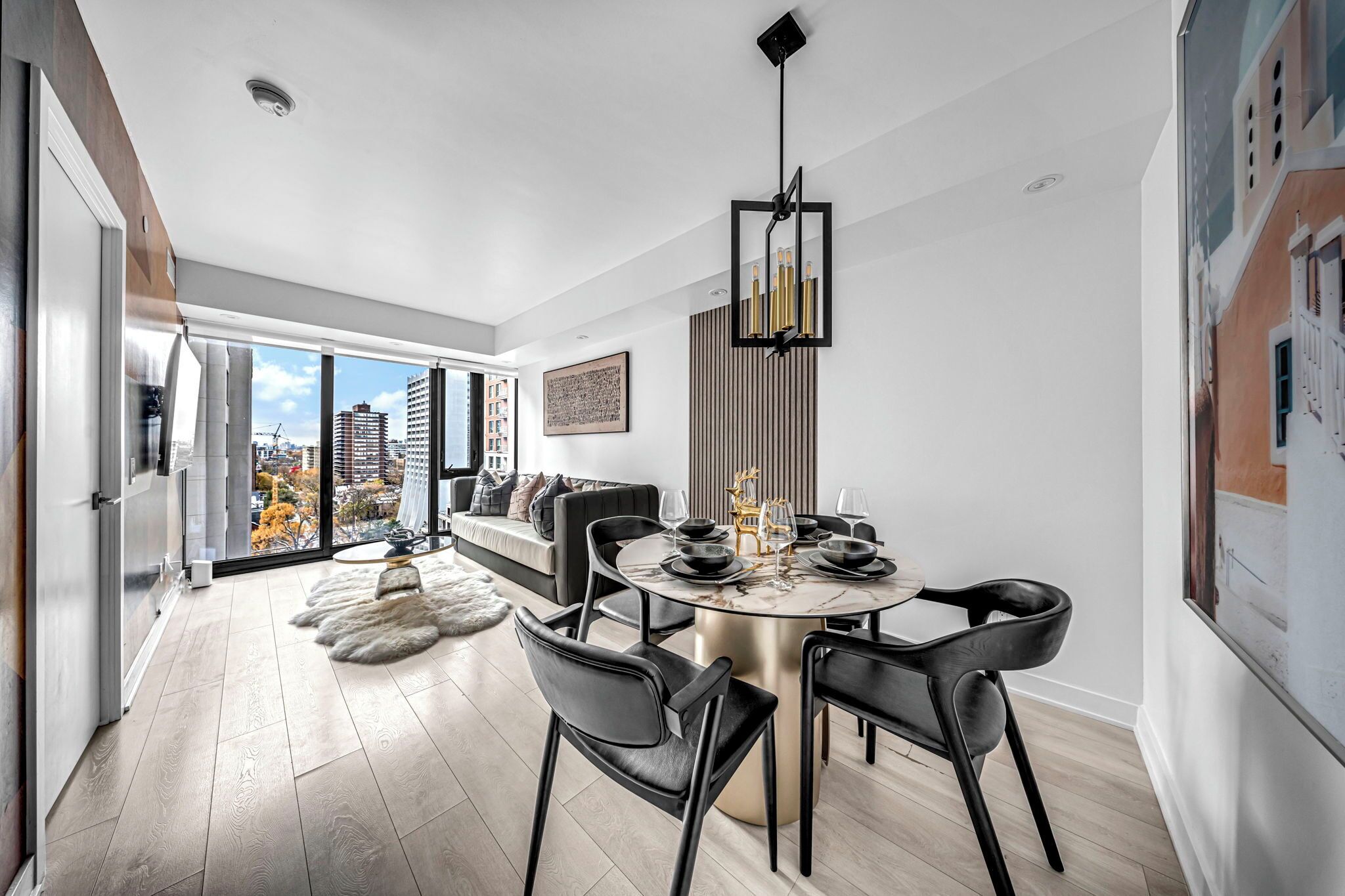 A modern dining area with a round table, black chairs, and a chandelier.