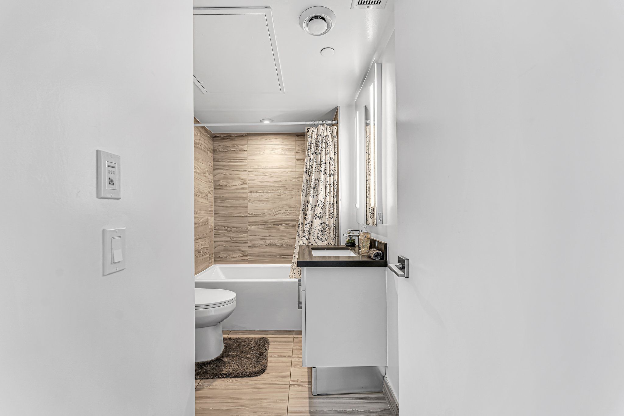 A modern bathroom with a toilet, bathtub, and a sink area.