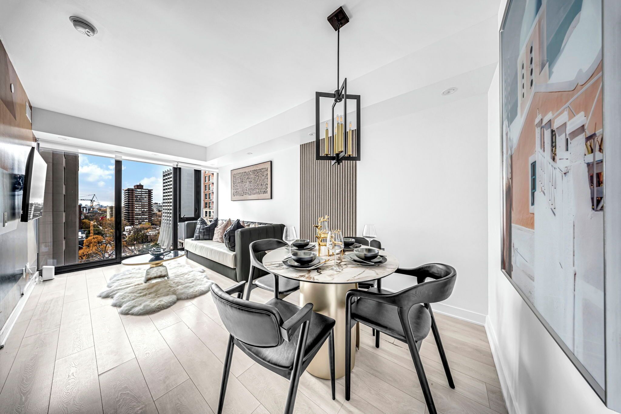 A modern dining area with a round table, black chairs, and a chandelier.