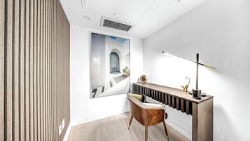 Una habitación moderna con pared de listones de madera, un cuadro grande enmarco, una consola elegante con lámpara y una silla con detalle dorado.