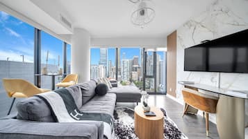 A modern living room with a large sofa, a coffee table, and a TV.