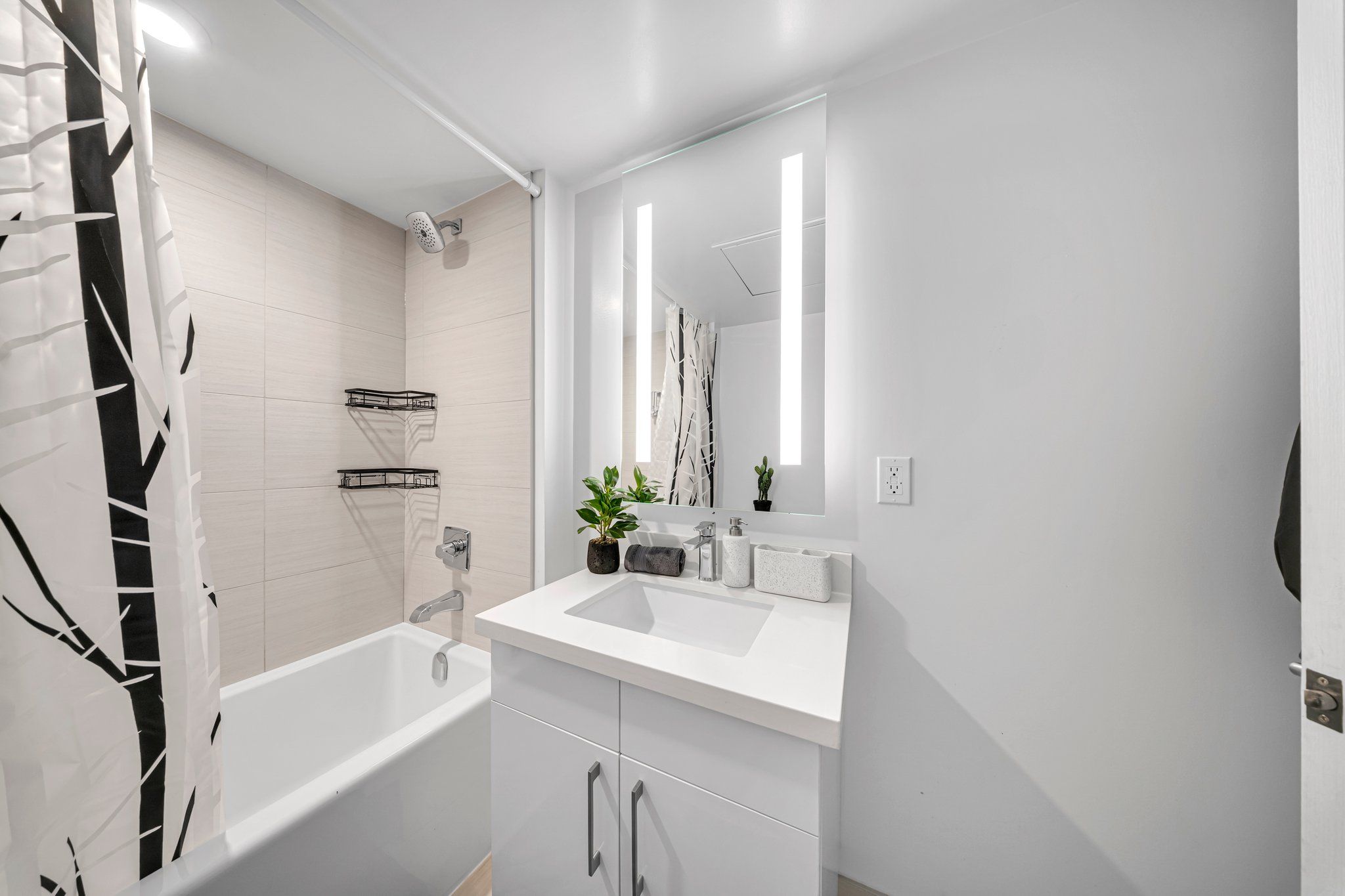 A modern bathroom with a white sink, mirror, and shower.