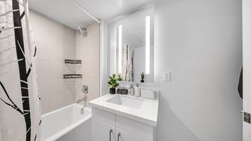 A modern bathroom with a white sink, mirror, and shower.