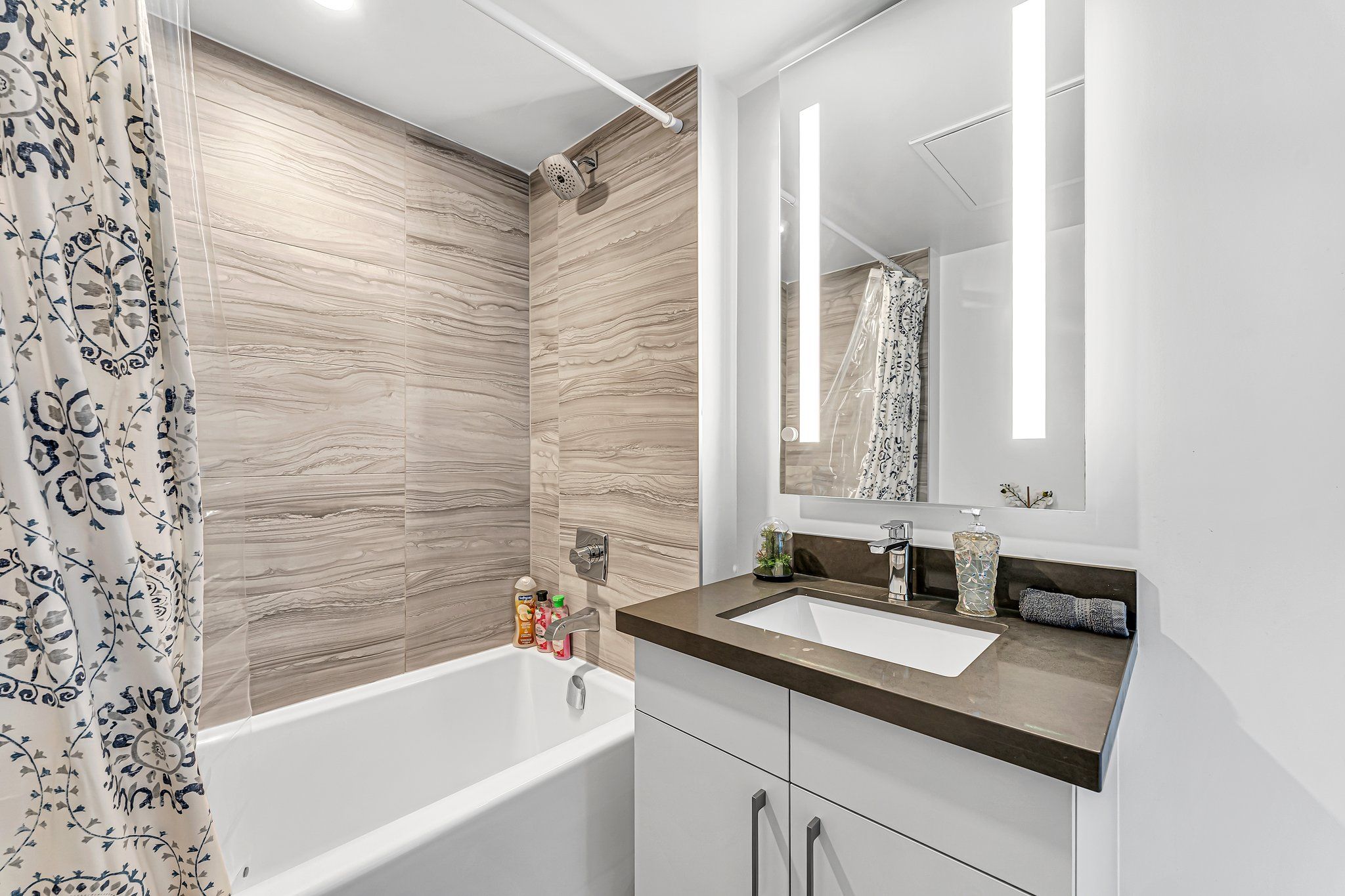 Un baño moderno con bañera, lavamanos y espejo.