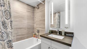 Un baño moderno con bañera, lavamanos y espejo.