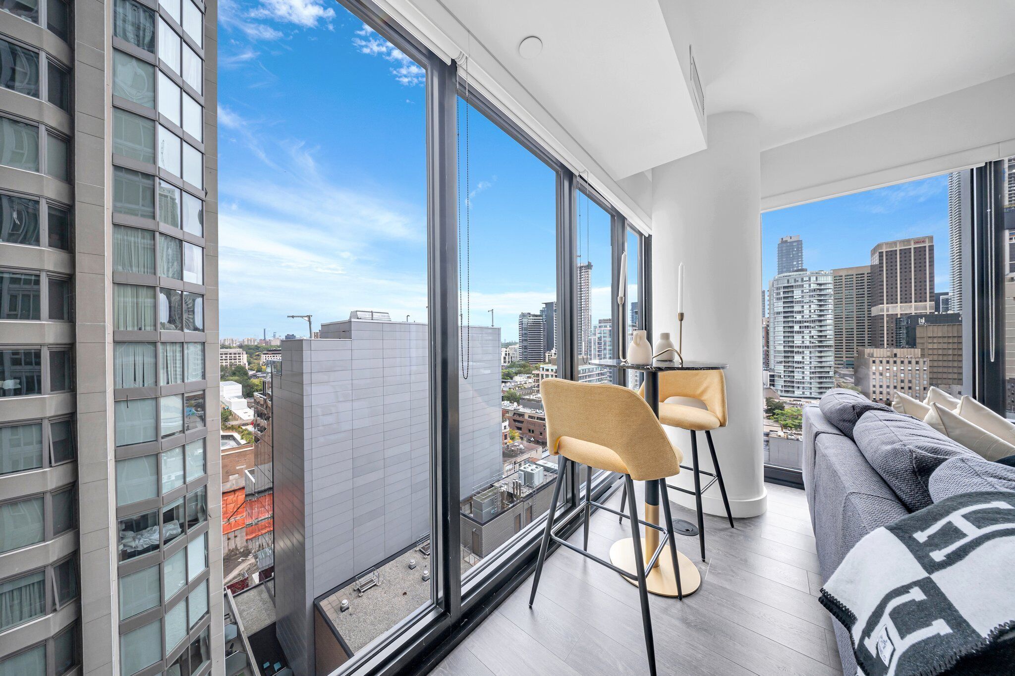 Un apartamento moderno con ventanas amplias, un sofá, un comedor y vistas a la ciudad.