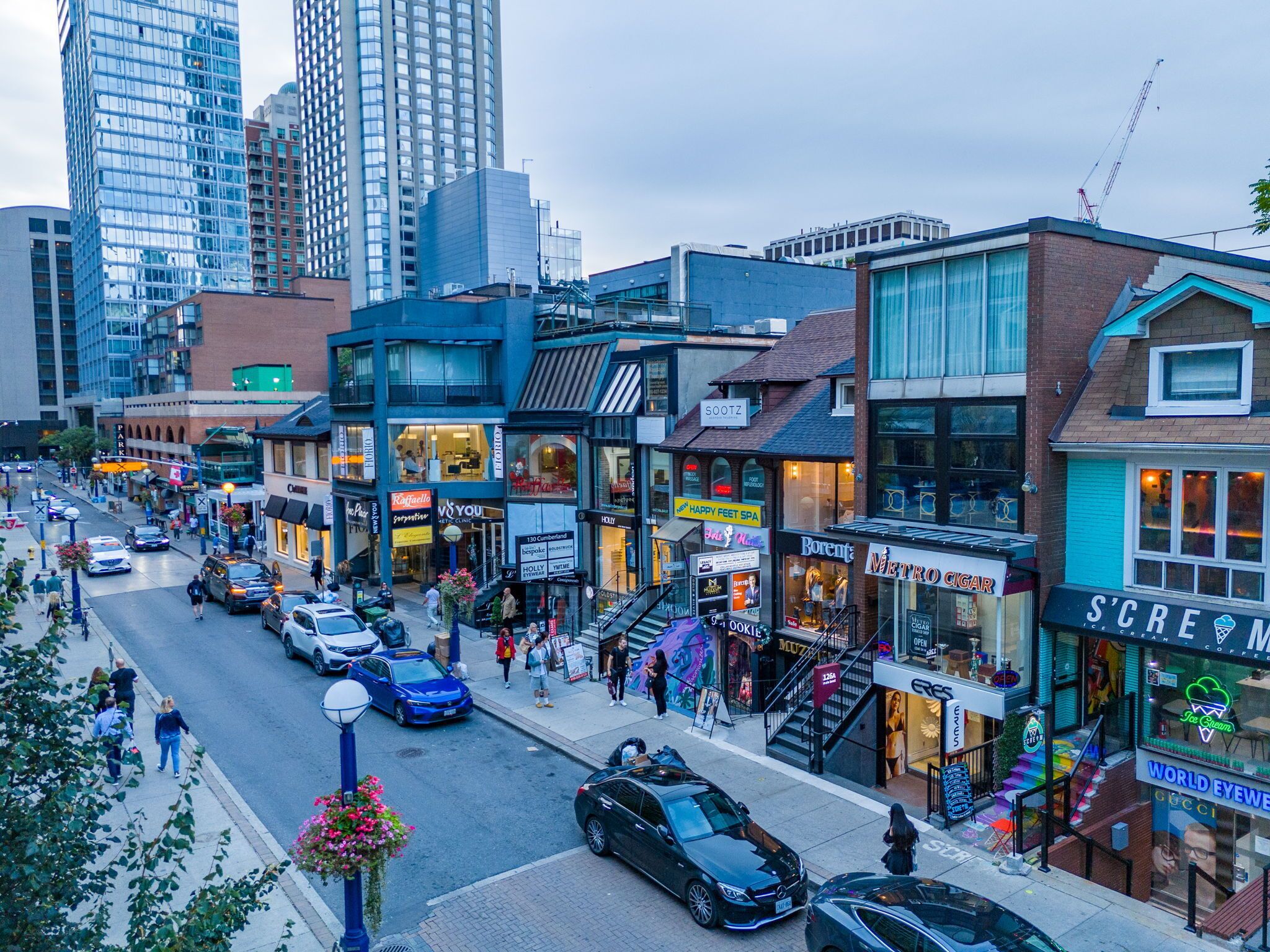 A busy urban street with various storefronts, including a visible pharmacy and a coffee shop.