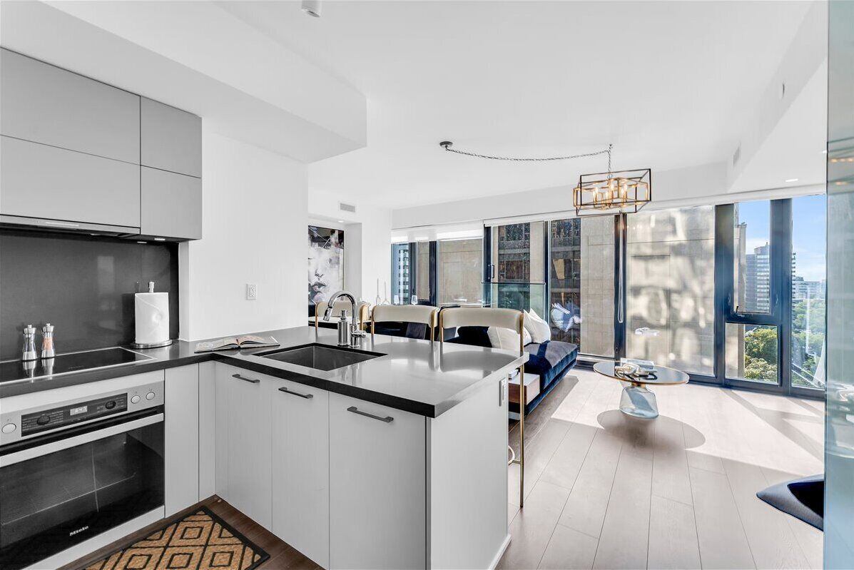 A modern kitchen with a central island, built-in oven, and a dining area with a view of the city.
