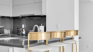 A modern kitchen with a central island, stainless steel appliances, and gold bar stools.