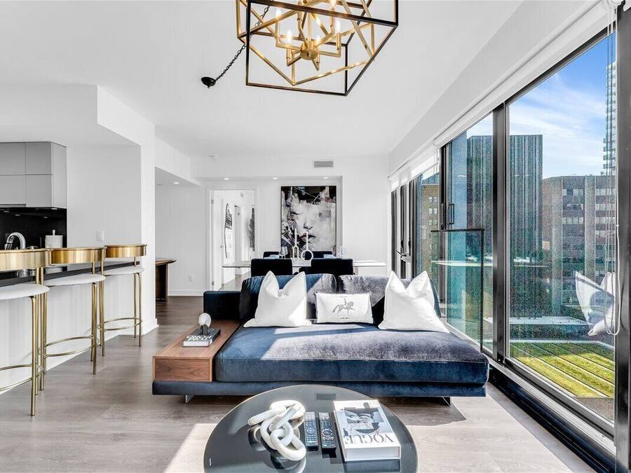 A modern living room with a sofa, a coffee table, and a view of the city through large windows.