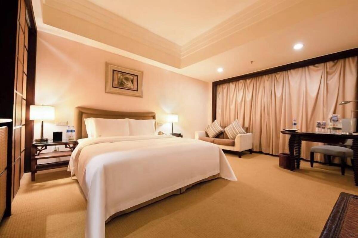 Ein Hotelzimmer mit einem großen Bett, einem Schreibtisch, einem Sessel, einer Couch und einer Lampe.