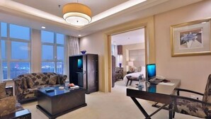 Een hotelkamer met een bank, een salontafel, een televisie, een bureau met een computer en een bed.