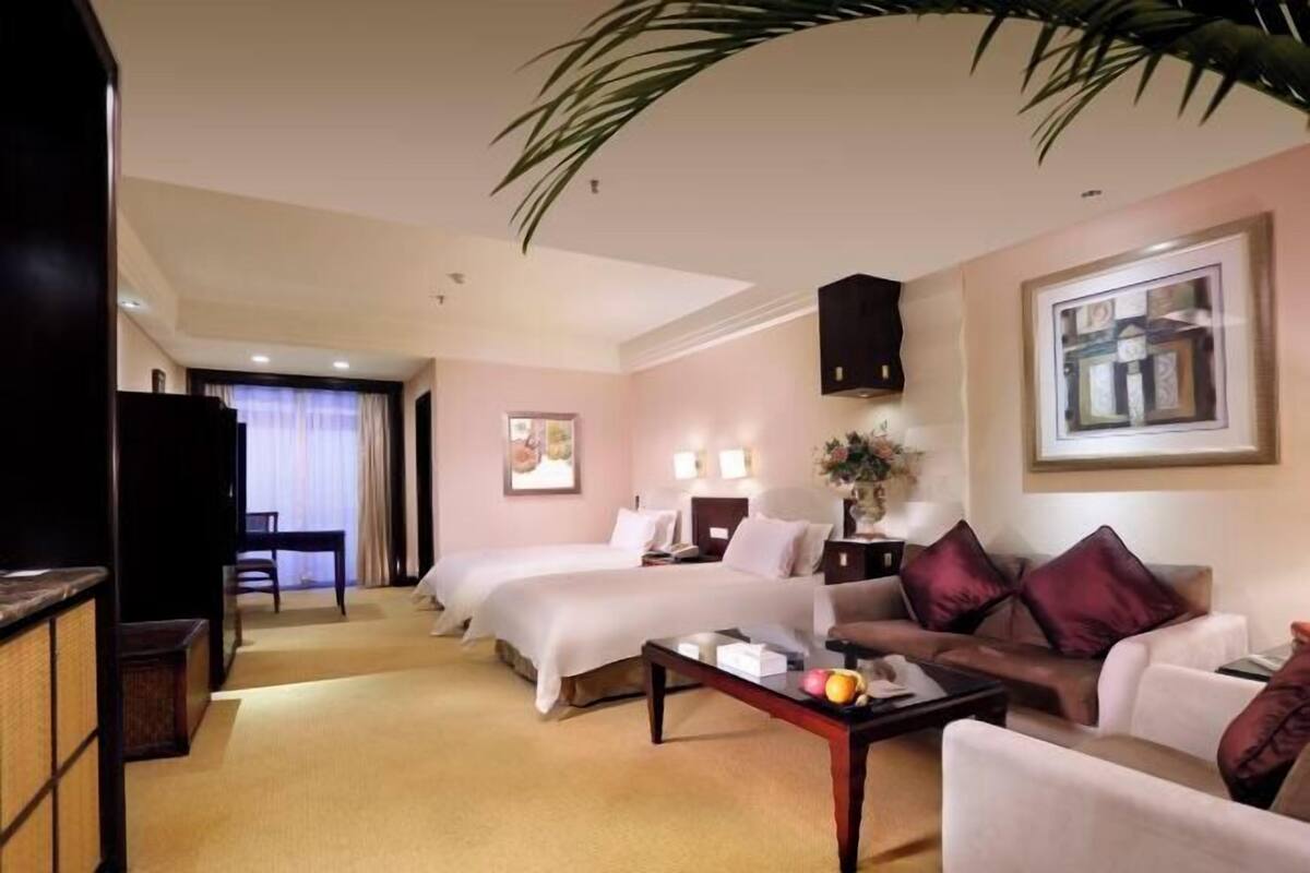 Ein Hotelzimmer mit zwei Betten, einem Schlafsofa, einem Couchtisch und einem Fernseher.