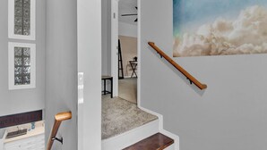 A staircase with a wooden handrail, a wall-mounted picture of clouds, and a door leading to another room. - Cloud 9 -- Cozy studio with WiFi, AC in charming Chuluota, FL (Chuluota)