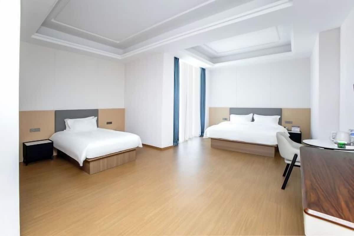 A hotel room with two beds, a desk, a chair, and a window with curtains.