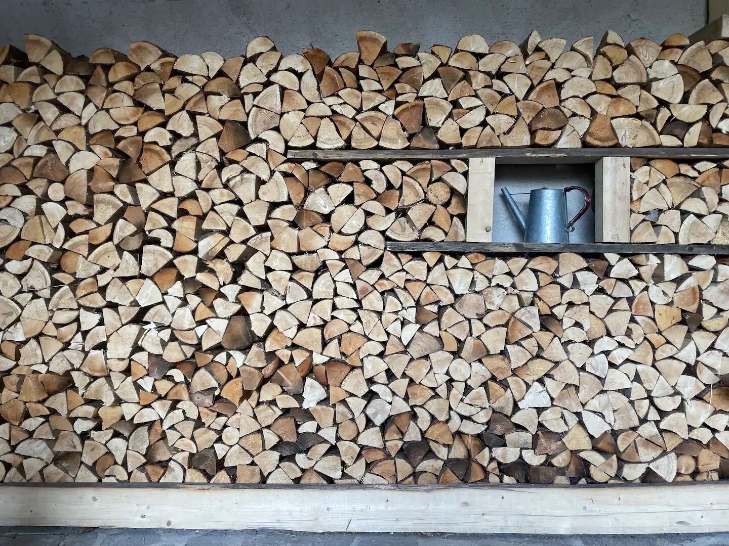 Une pile de bois de chauffage, soigneusement coupé, est posée contre un mur.