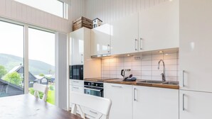 Una cucina moderna con mobili bianchi, un piano di lavoro in legno e un'ampia finestra con vista panoramica.