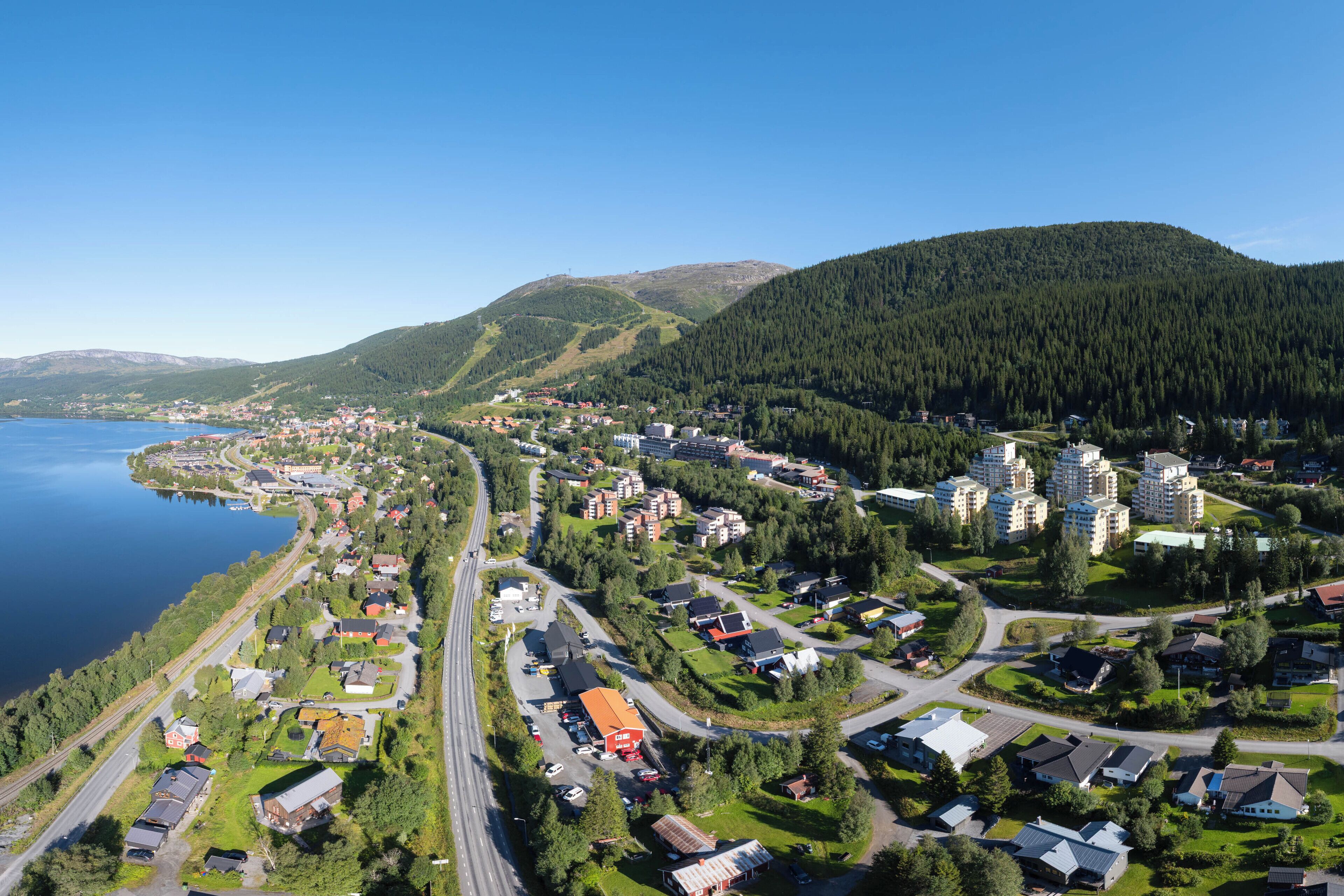 Luftaufnahme einer Küstenstadt mit Wohnhäusern, einer Straße und einem Gewässer.