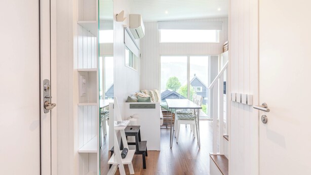 Una cucina moderna con mobili bianchi, un'area pranzo con tavolo e sedie, e vista sulle case circostanti.