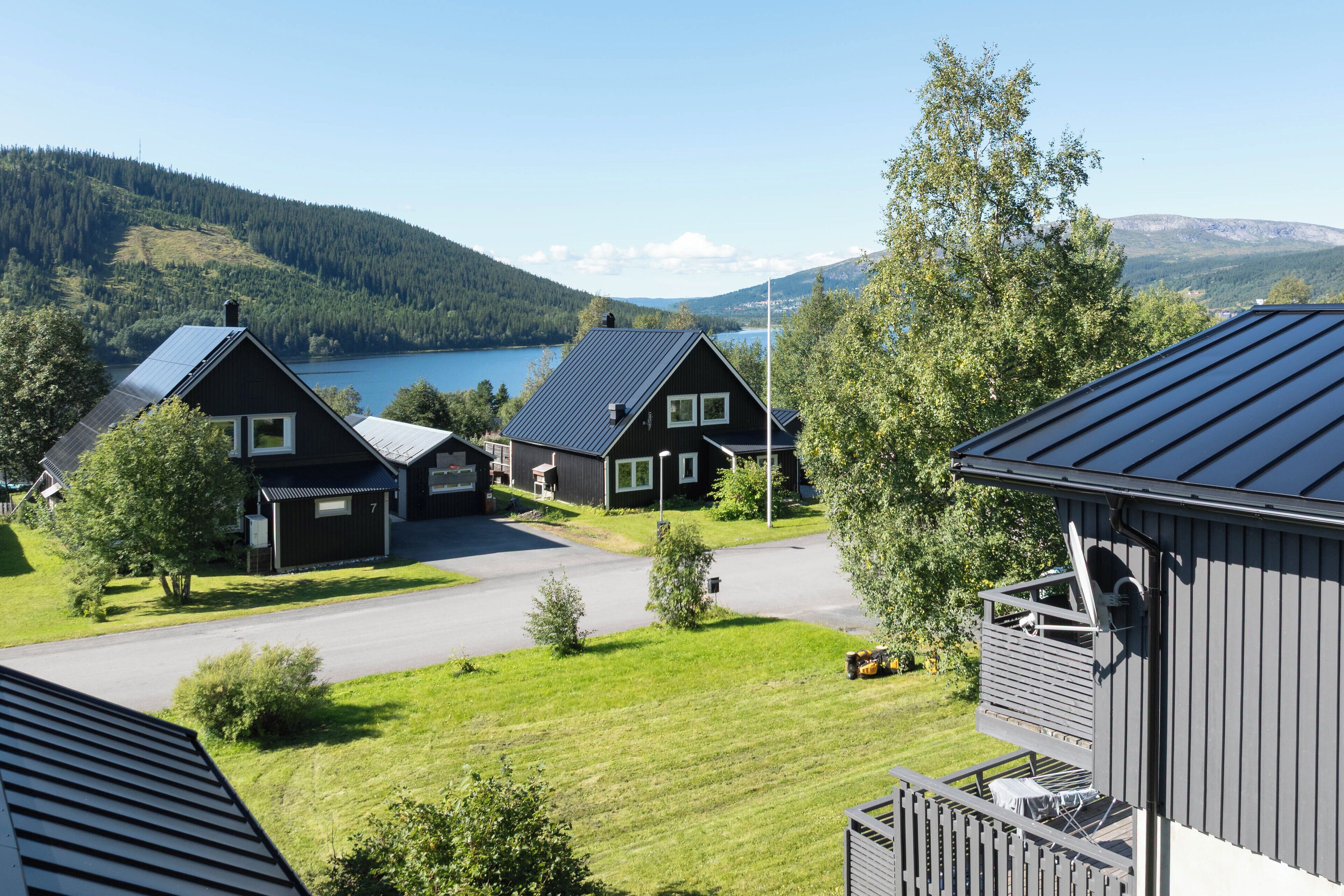 A residential area with houses, a clear sky, and a lake in the background.