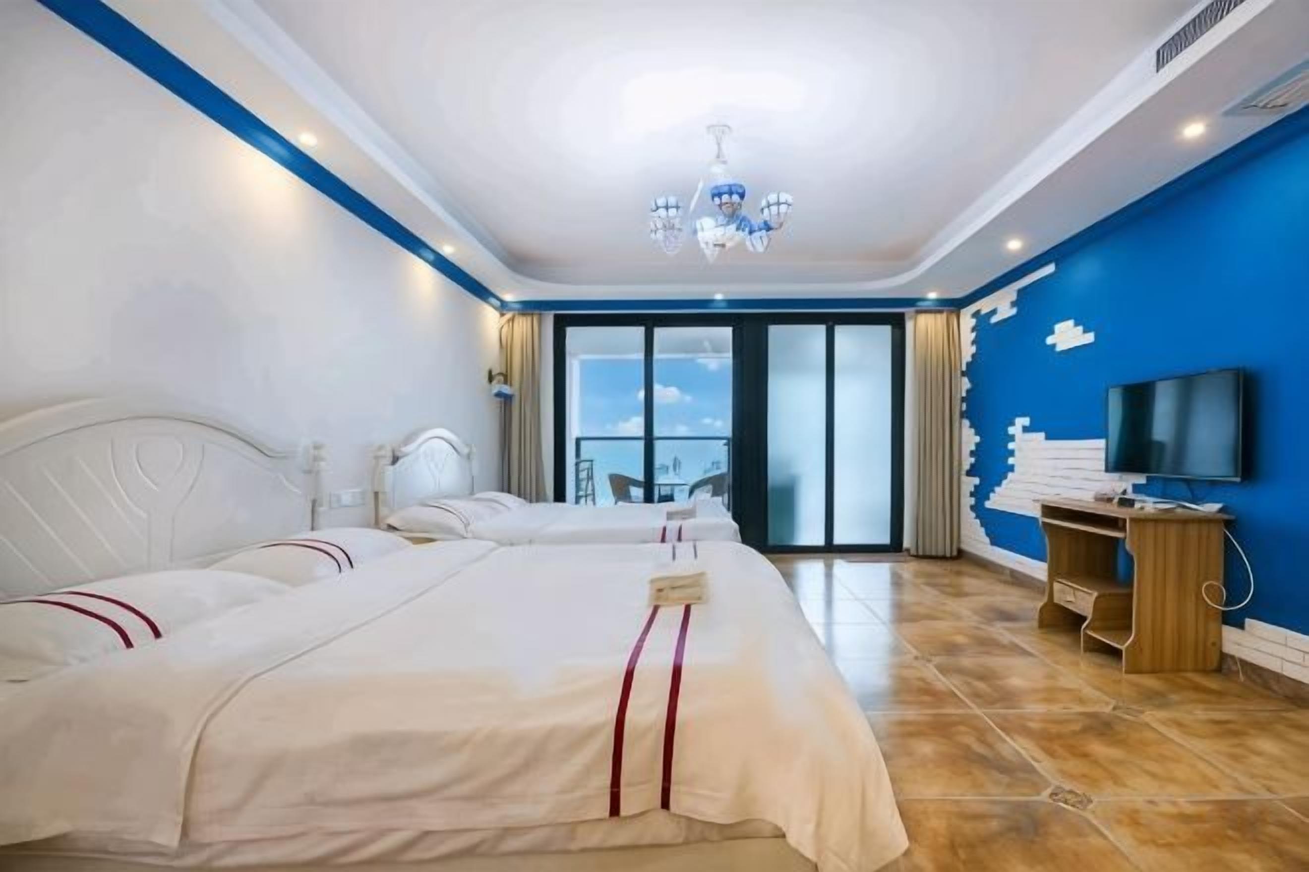A hotel room with a large bed, a desk, a TV, and a balcony with a view.