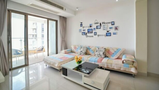 A modern living room with a sofa set, a coffee table with flowers, and a wall decorated with framed photos and a 'House Dream' sign. - Beihai Beibu Gulf No.1 Yazhijia Scenic Apartment (Beihai)