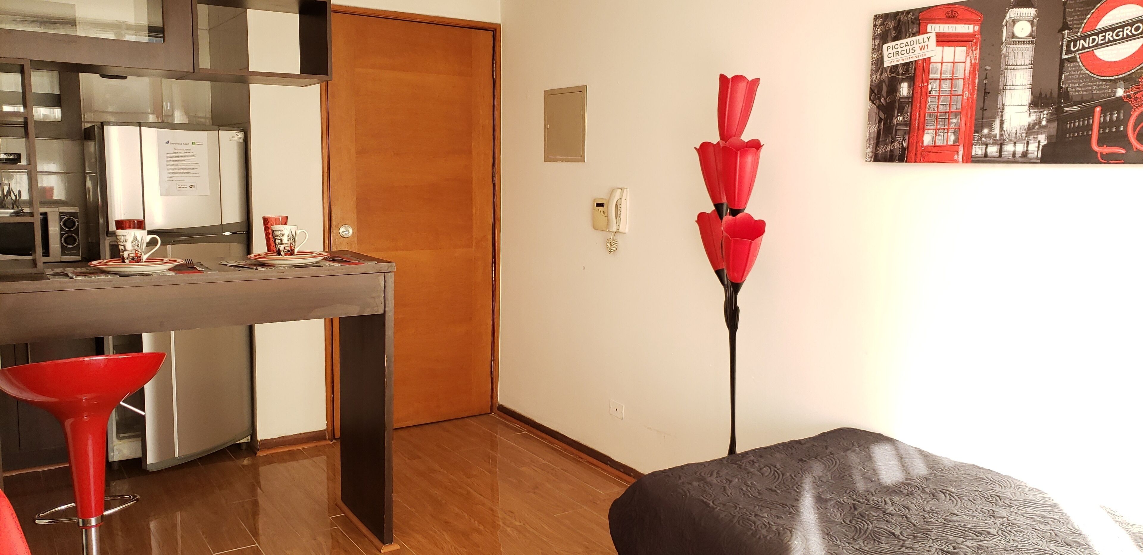 A modern kitchen with a refrigerator, a wooden door, and a dining area with a table and chairs.