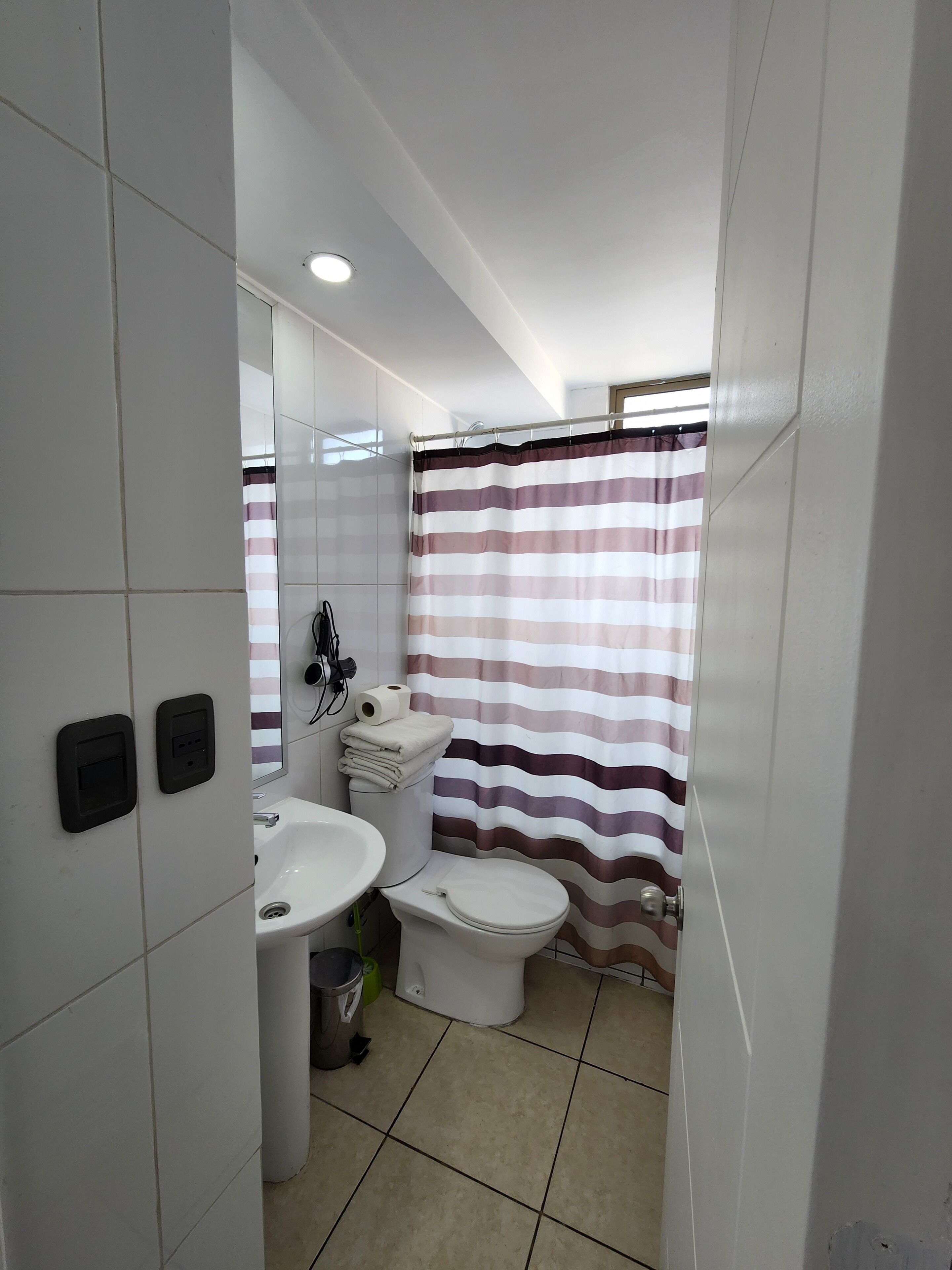 A small bathroom with a white sink, toilet, and striped shower curtain.