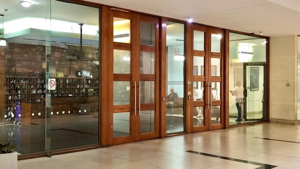 Eine Lobby mit Glastür, einer Rezeption und einer Sitzecke.