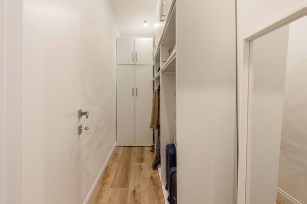 A narrow hallway with a wooden floor, white walls, and a closet with open shelves. - Fiammetta by Mmega (Florence)