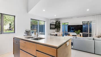 A modern kitchen with a central island, built-in dishwasher, and a dining area with a table and chairs.