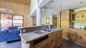 A modern kitchen with wooden cabinets, a built-in dishwasher, and a large island with a sink. - APARTMENT BALCONS DU MONT D'EVIAN - 8 PEOPLE - ST JEAN D'AULPS VILLAGE (Saint-Jean-d´Aulps)