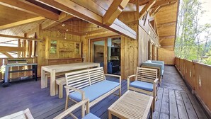 A wooden deck with seating and a table, a wooden interior with a door leading outside, and a view of trees. - APARTMENT BALCONS DU MONT D'EVIAN - 8 PEOPLE - ST JEAN D'AULPS VILLAGE (Saint-Jean-d´Aulps)