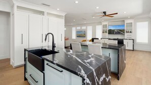 A modern kitchen with white cabinetry, a black marble island, and a ceiling fan. - BEAUTIFUL never before seen golf course home in "THE GRAND" (Surprise)