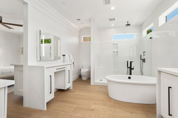 A modern bathroom with a freestanding bathtub, a toilet, and a vanity with a mirror. - BEAUTIFUL never before seen golf course home in "THE GRAND" (Surprise)