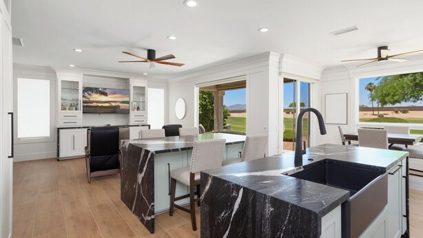 A modern kitchen with marble countertops, a built-in island, and a view of the outdoors. - BEAUTIFUL never before seen golf course home in "THE GRAND" (Surprise)